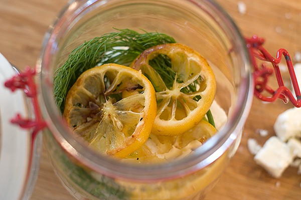 Roasted lemons on top of other ingredients in jar.