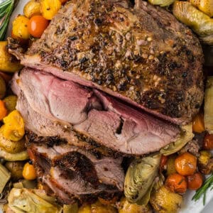 Finished leg of lamb on a bed of vegetables.