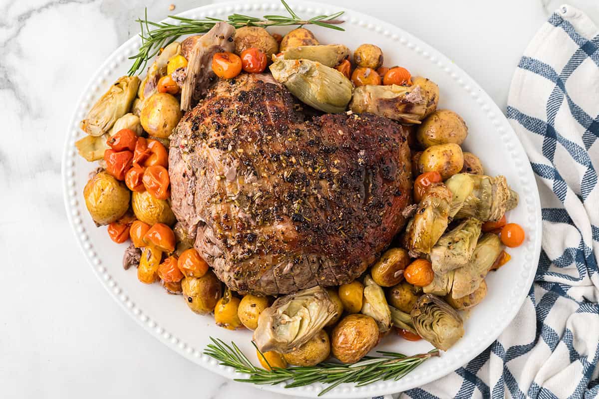Finished leg of lamb on a bed of vegetables.