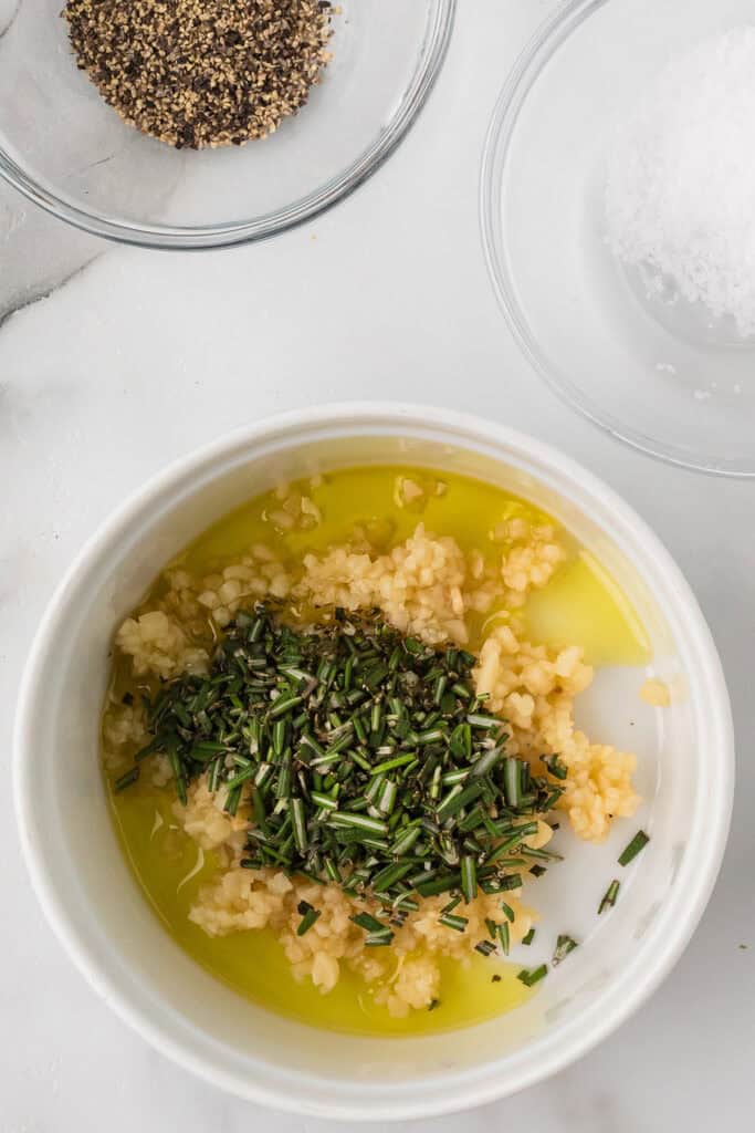 Garlic, rosemary, and olive oil mixture in a bowl.