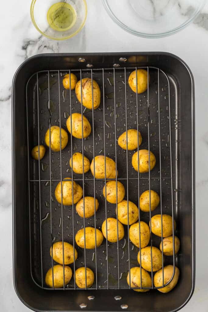 Small potatoes and olive oil in a roasting pan.
