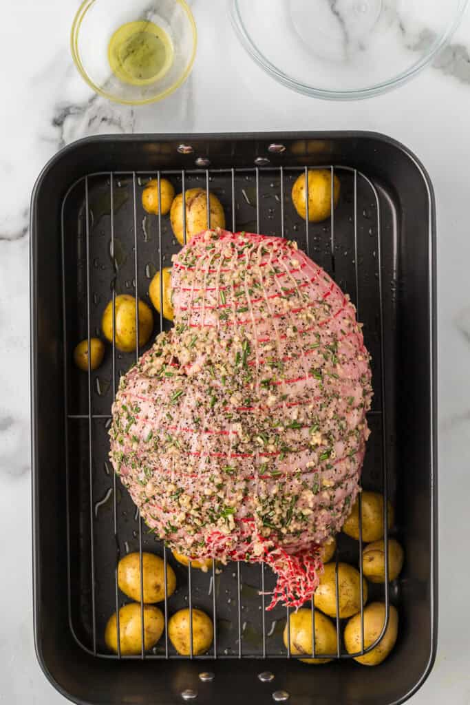 Prepared leg of lamb on a wire rack in the roasting pan.