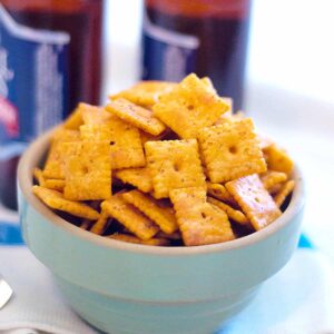 Cheese crackers in a vintage serving bowl with two bottles in the background.