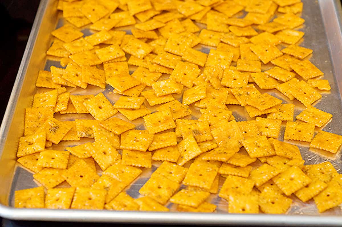 Coated crackers spread on a baking sheet.