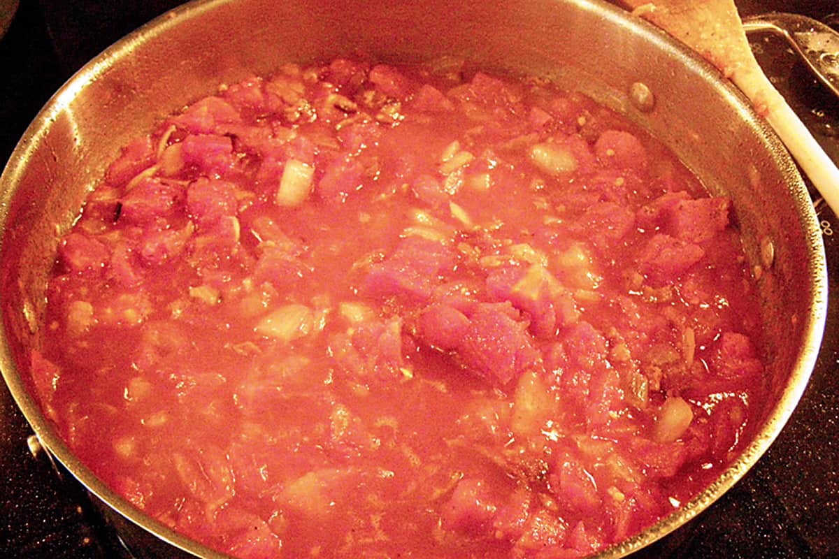 Tomatoes added to the arrabiata sauce in a skillet.