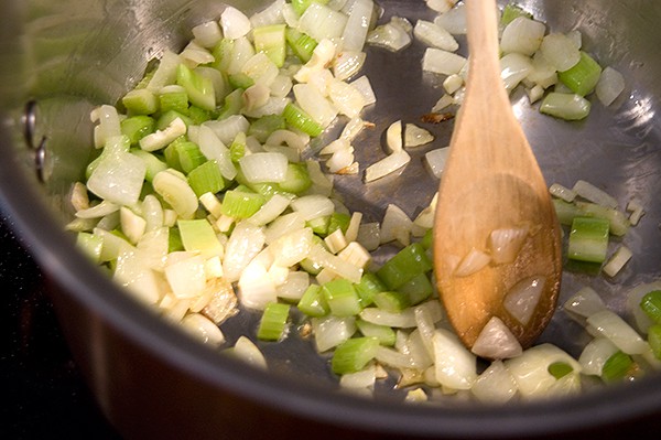 Onions and celery sauteing in a skillet.