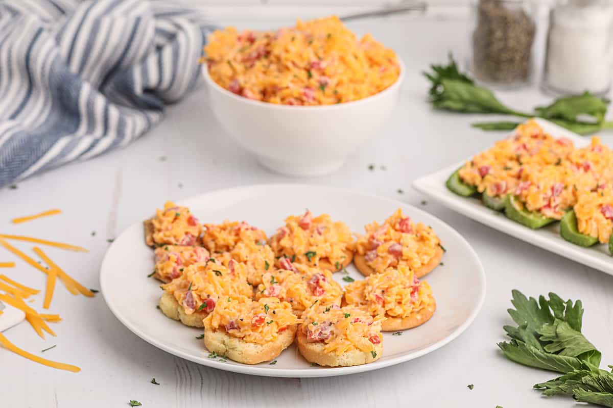 Pimiento cheese on crackers on a serving plate.