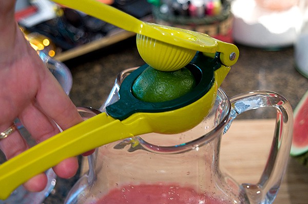 Squeezing the juice of a fresh lime into the pitcher.