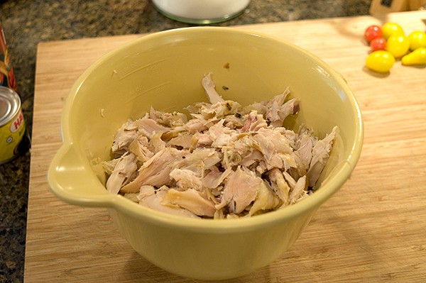 Shredded meat from a rotisserie chicken in a bowl.