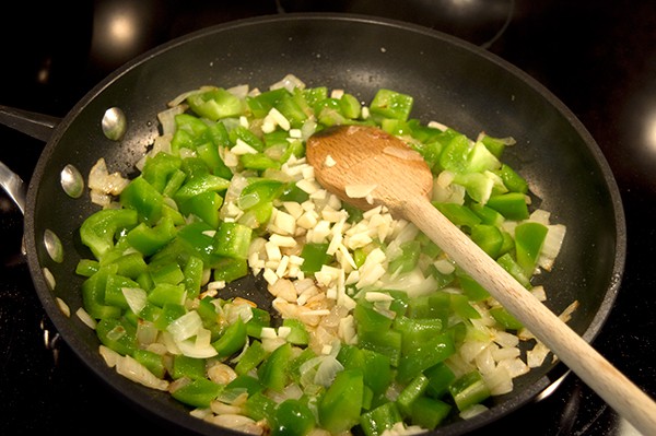 Onion and peppers being sauteed in a skillet.