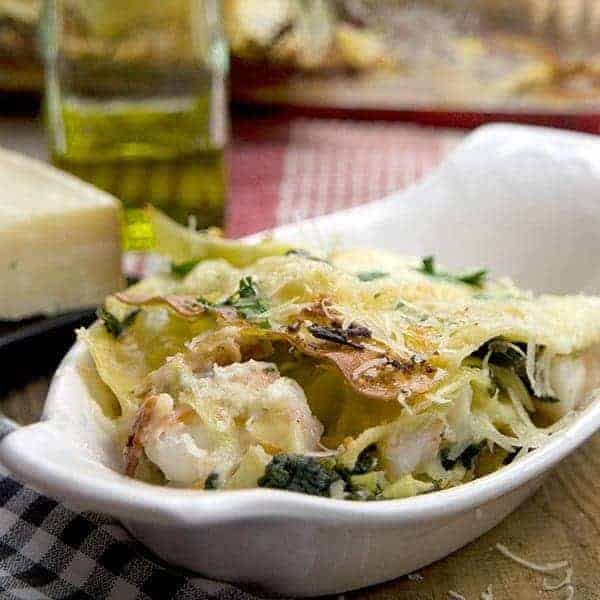 A non-traditional lasagna featuring artichoke hearts, spinach, shrimp, bacon, and Ragu's Light Parmesan Alfredo sauce. https://www.lanascooking.com-artichoke-spinach-shrimp-bacon-lasagna