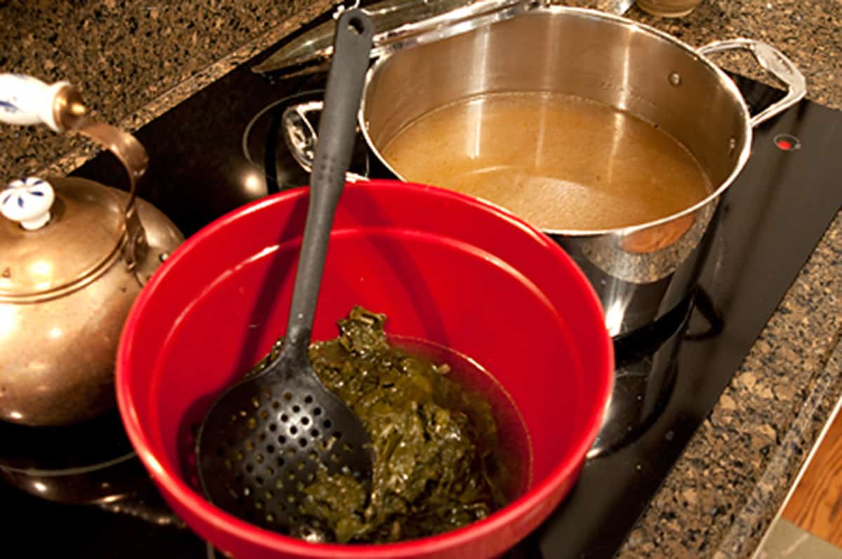 Removing turnip greens from the cooking pot to a bowl.