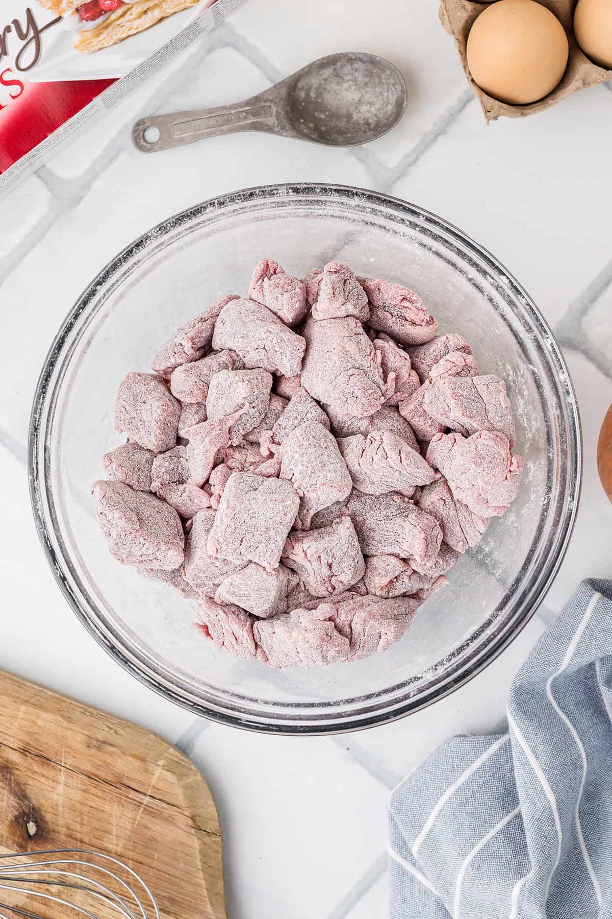 Beef tossed with flour mixture in a bowl.