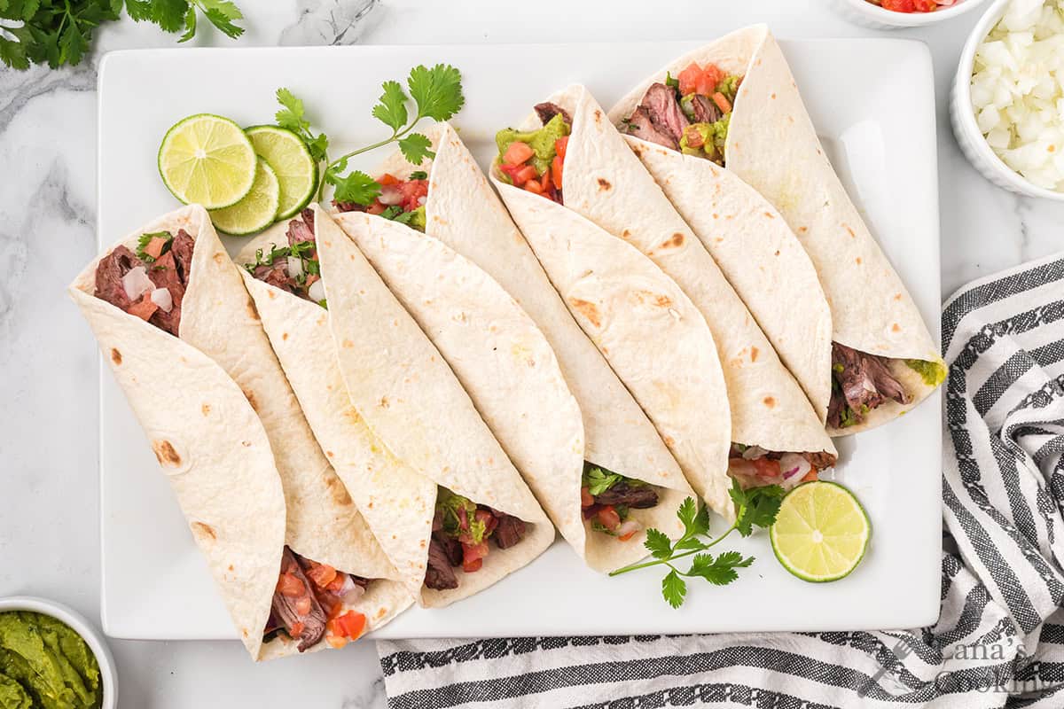 Tacos on a white serving plate.