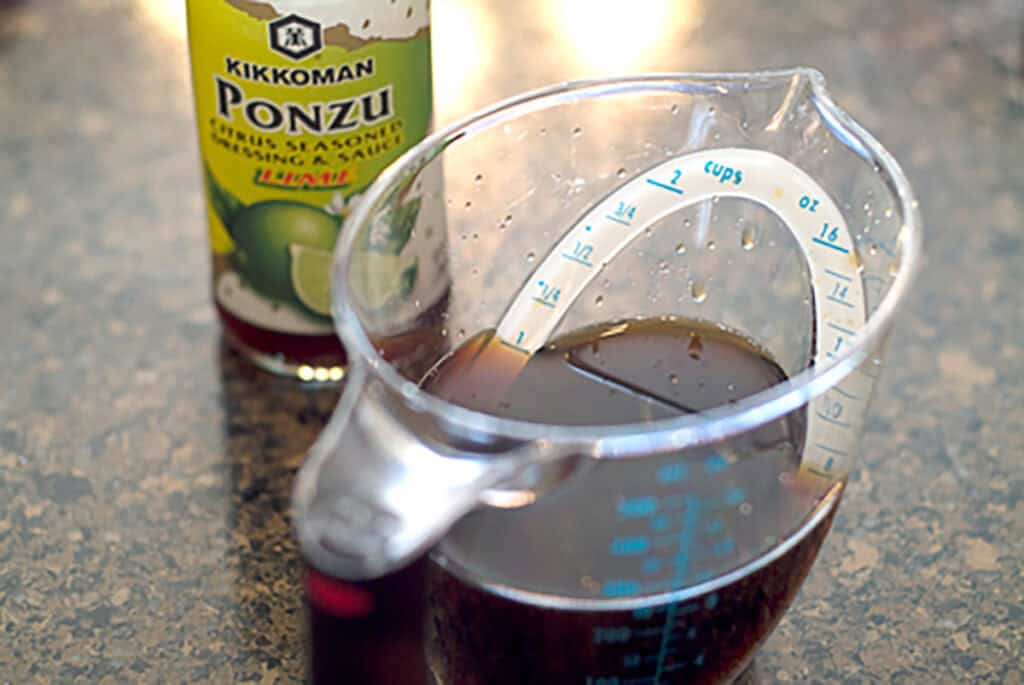 Lime ponzu sauce in the bottle and in a measuring cup.