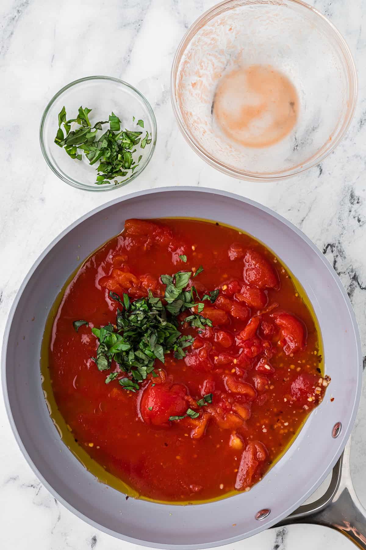 Basil added to the tomatoes, garlic, and red pepper flakes in the skillet.