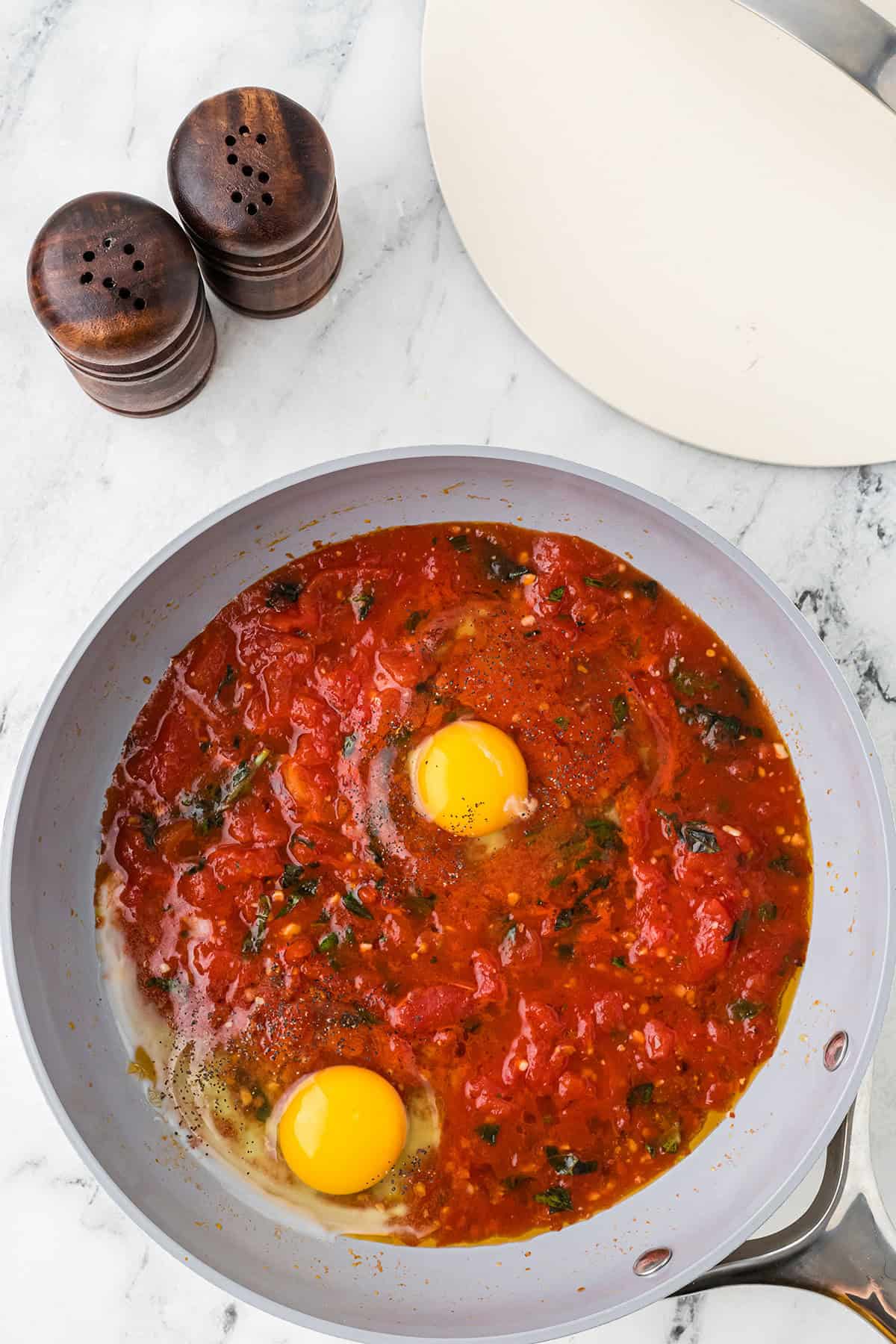 Eggs added to the simmering sauce in the skillet.
