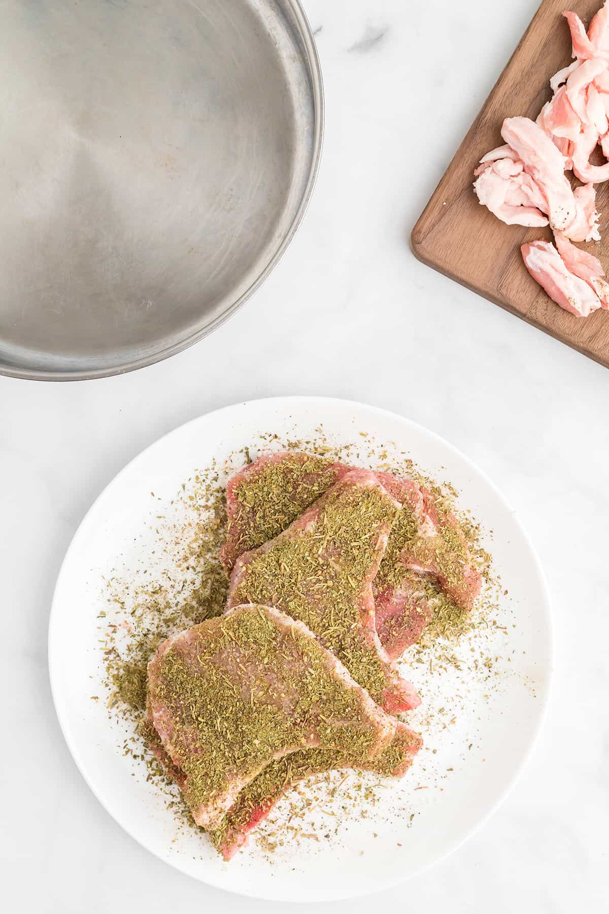 Trimmed pork chops sprinkled with seasonings.