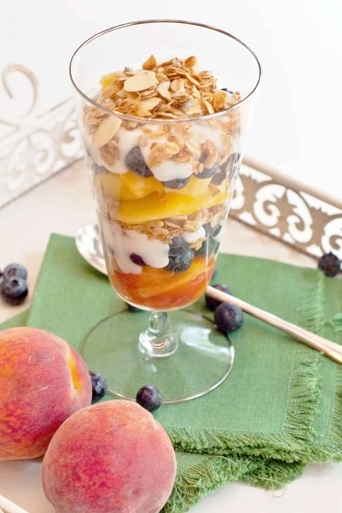 Parfait in a tall glass with a spoon on a tray.