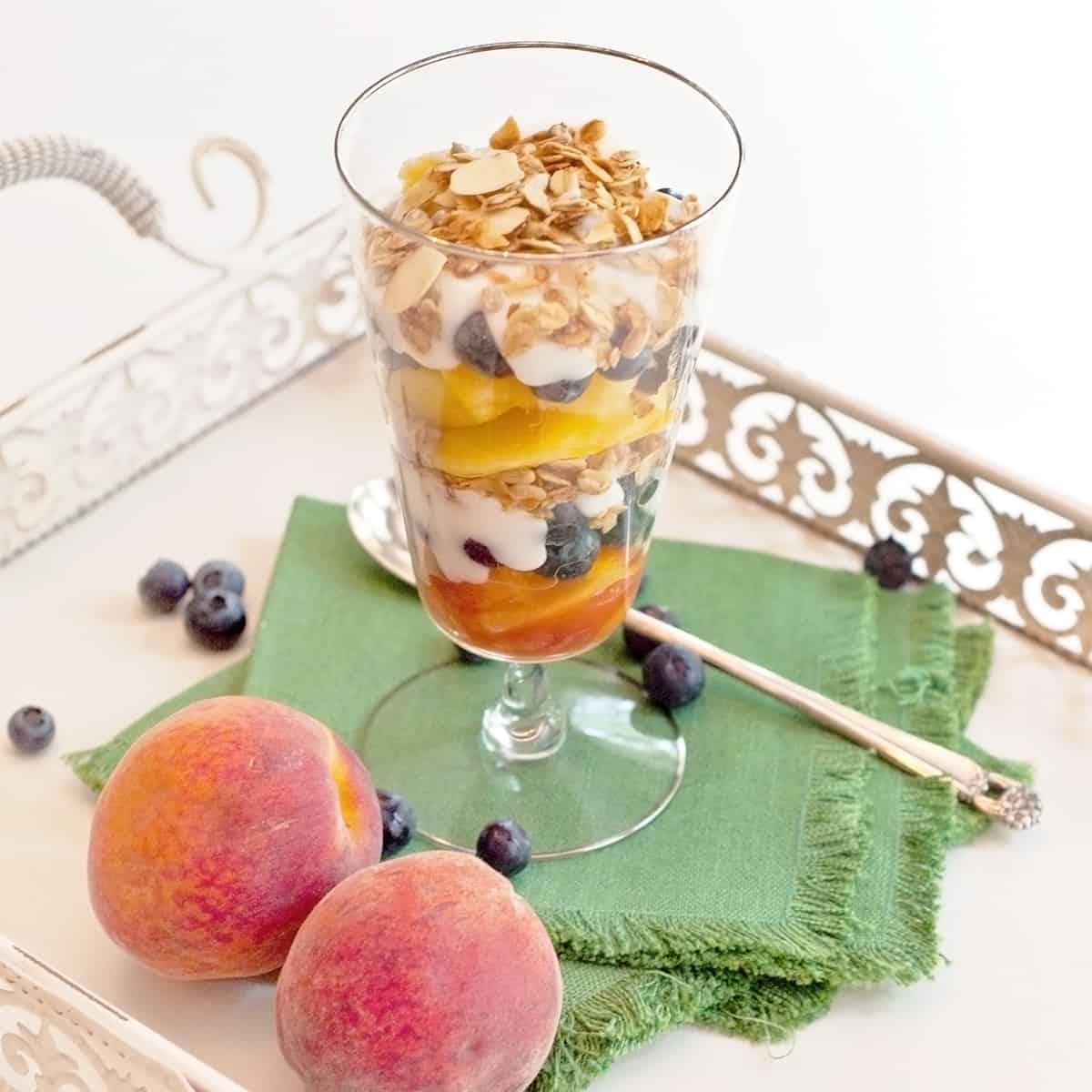 Parfait in a tall glass with a spoon on a tray.