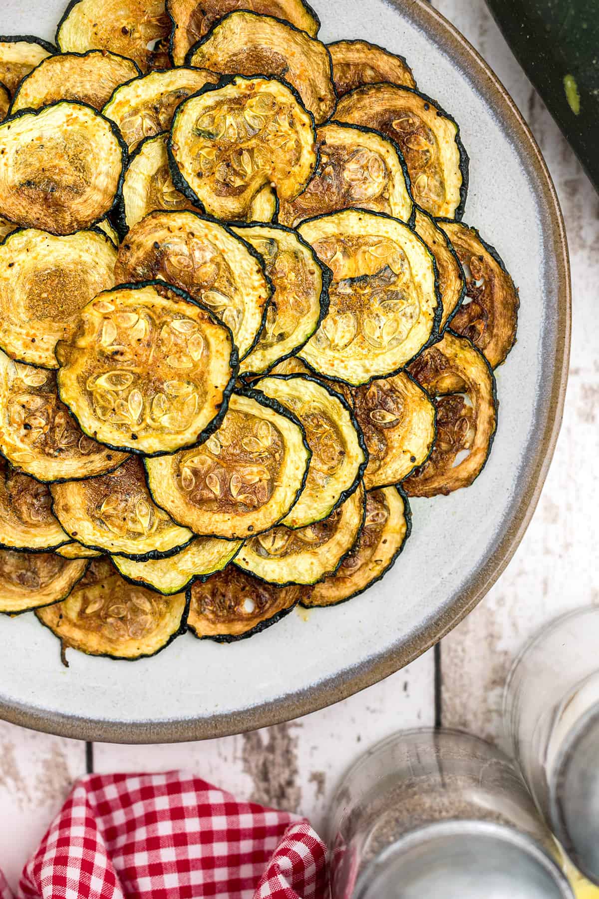 Finished zucchini chips on a white plate.