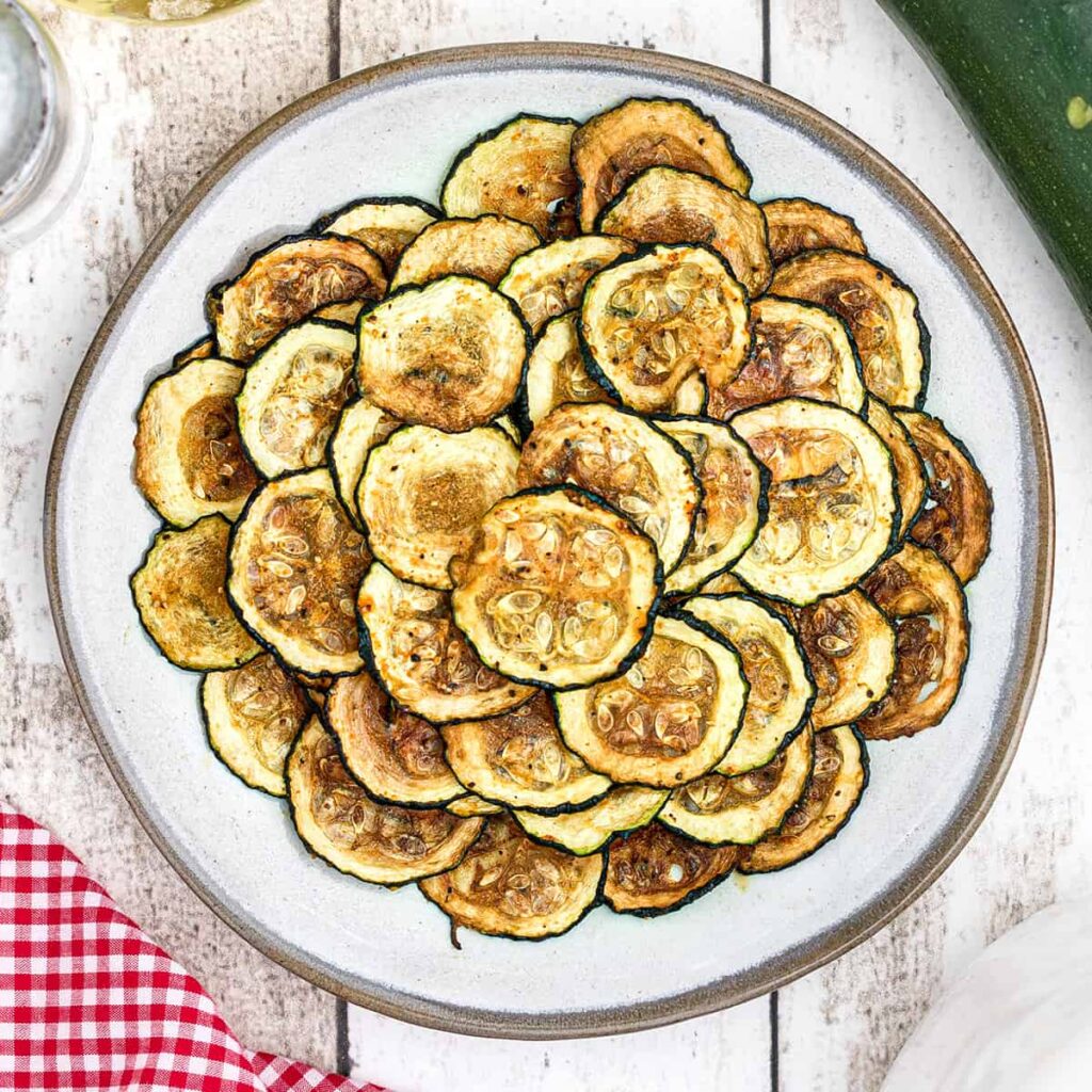 Finished zucchini chips on a white plate.