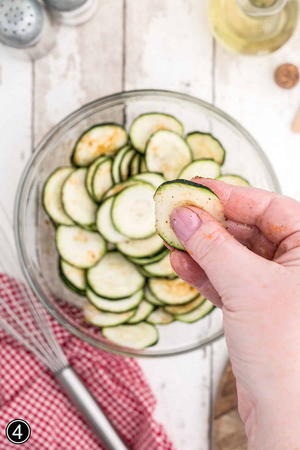 Tossing zucchini chips with oil and spices.