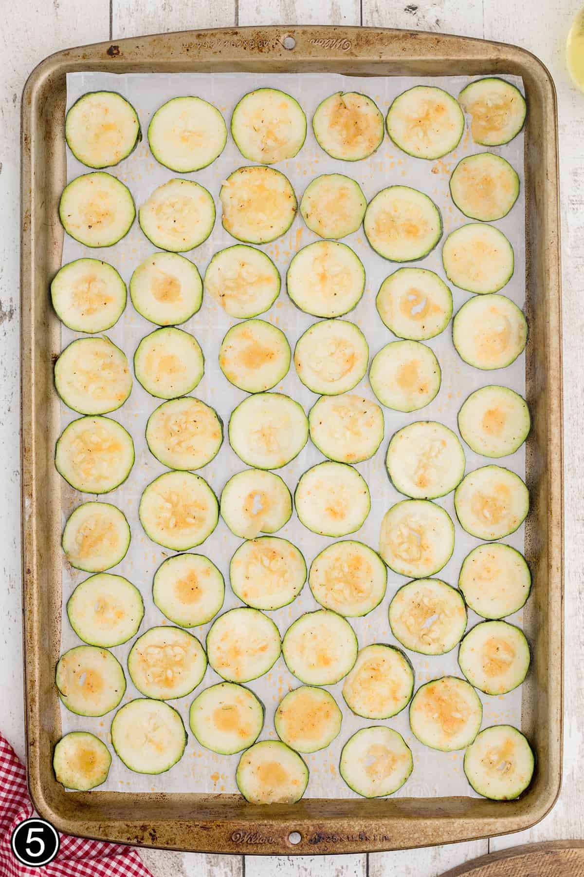 Zucchini chips on a lined baking sheet.