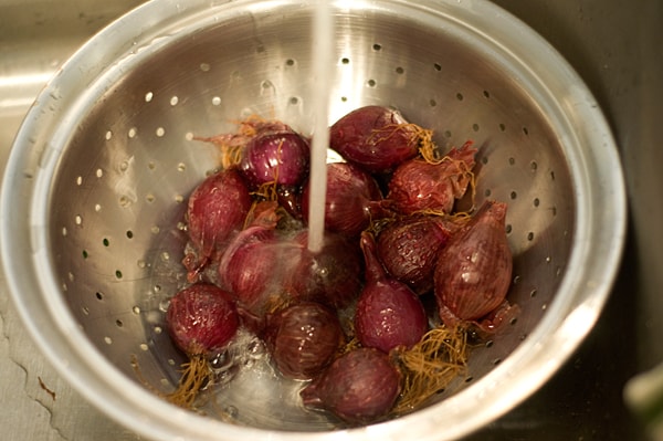 Rinsing red onions in a colander.