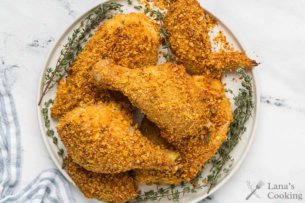 Plate of crispy baked chicken pieces on a white plate with sprigs of fresh thyme, viewed from above.