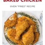 Plate of golden, crispy baked chicken pieces garnished with fresh herbs on a white marble background.