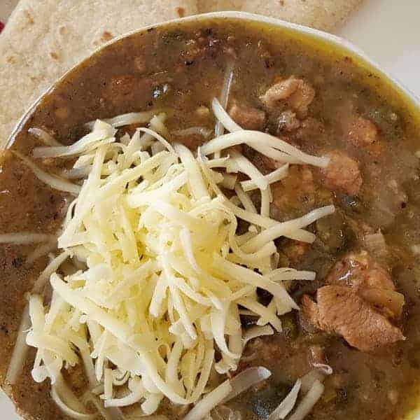 A serving of chili verde with tortilla and cheese.