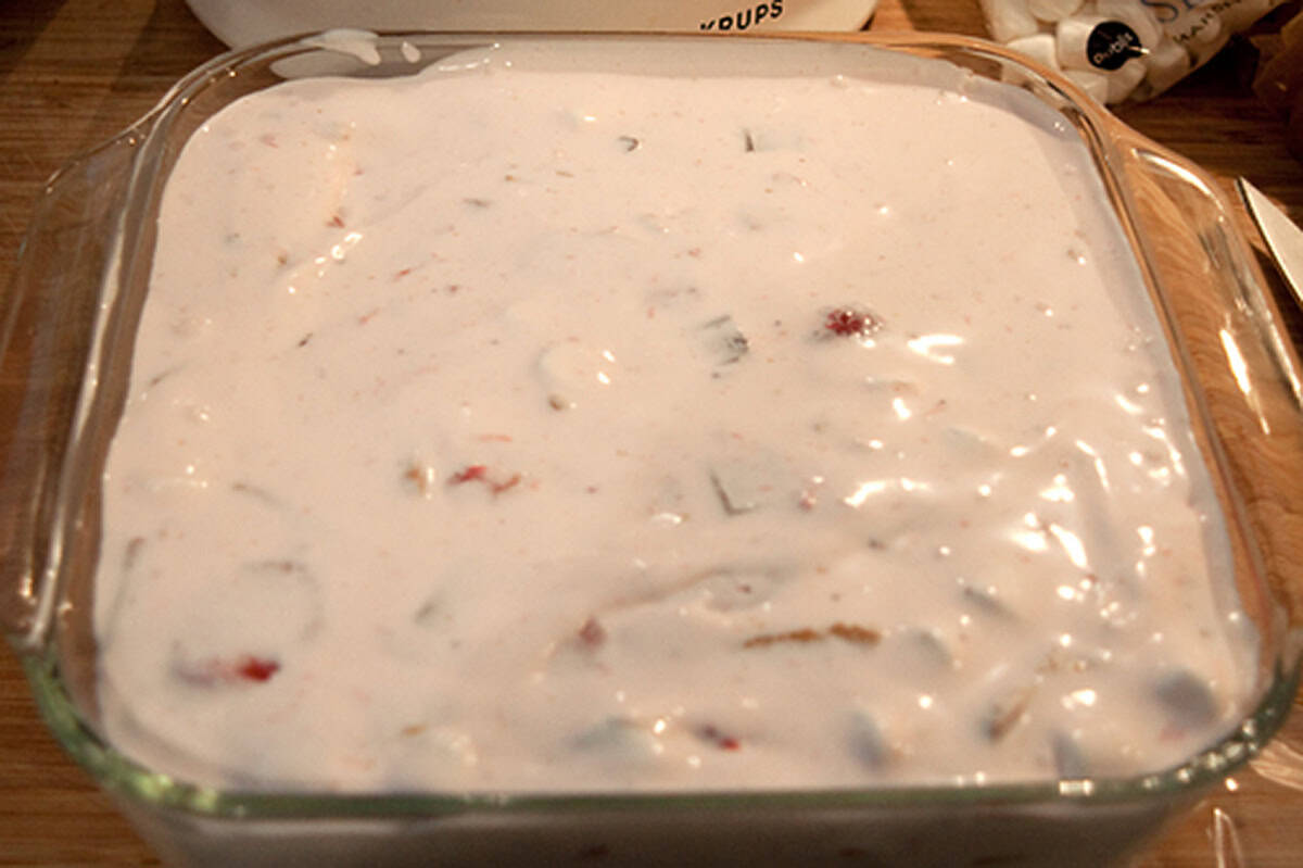 A glass baking dish filled with strawberry s'mores ice cream containing visible bits of chocolate, strawberries, and graham crackers.