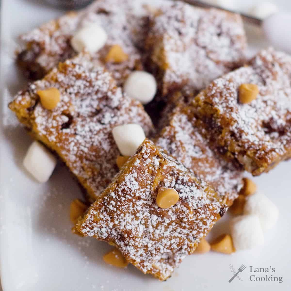 Butterscotch brownies arranged on a white plate.