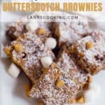 A plate of butterscotch brownies topped with powdered sugar, butterscotch chips, and mini marshmallows on a white dish.