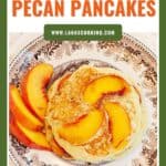 Plate of pancakes topped with peach slices, served with extra peach slices on a decorative plate.