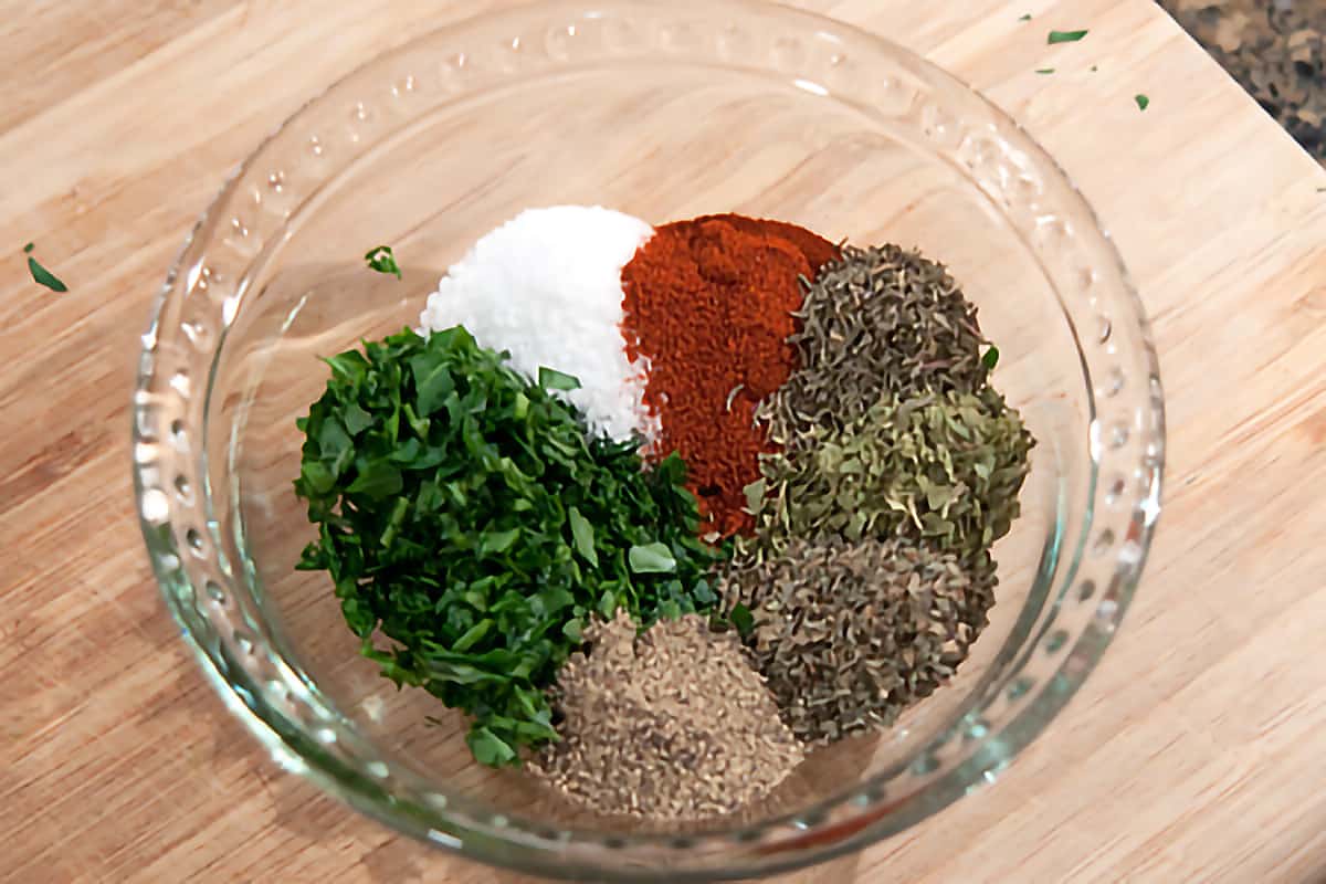 Small bowl with parsley, salt, paprika, thyme, oregano, basil and pepper needed for recipe