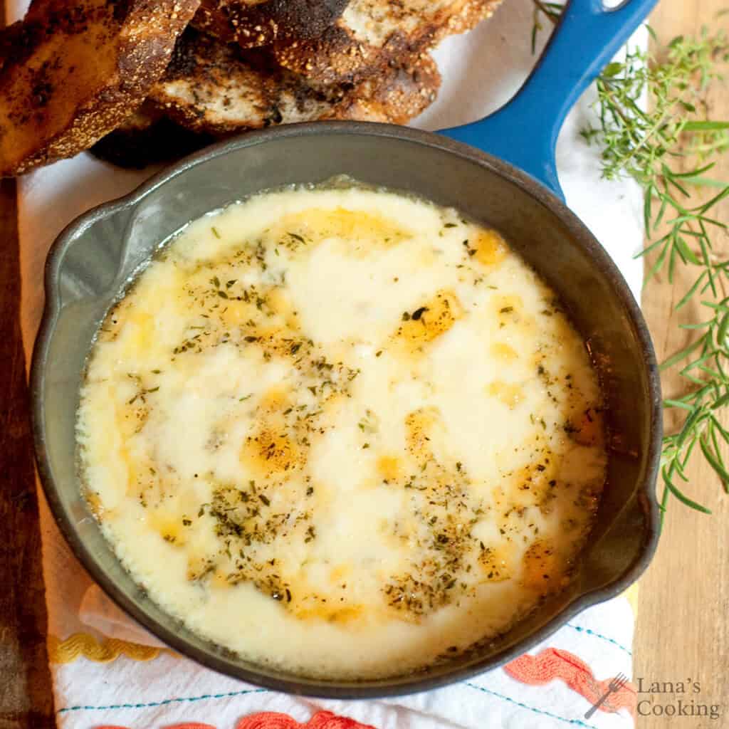 Baked fontina in a small cast iron skillet with toasted baguette on the side.