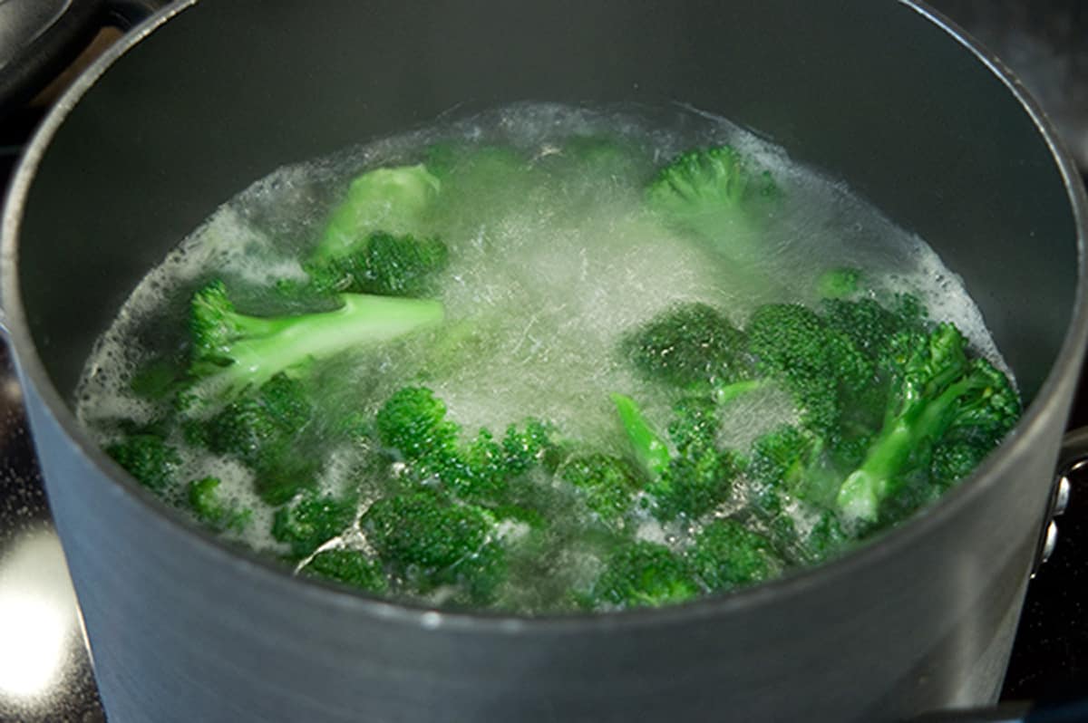 Fresh broccoli boiling in a saucepan.