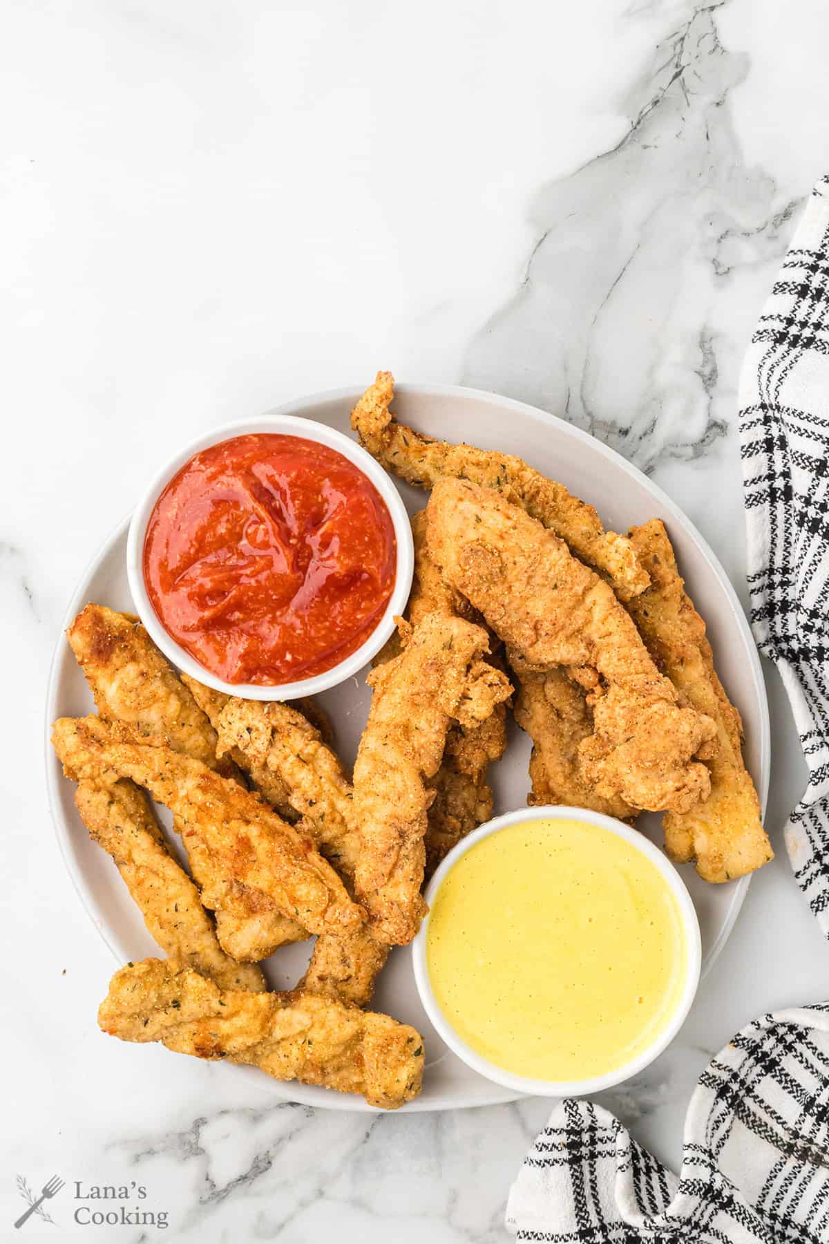 Finished fried chicken fingers with dipping sauces on the side.