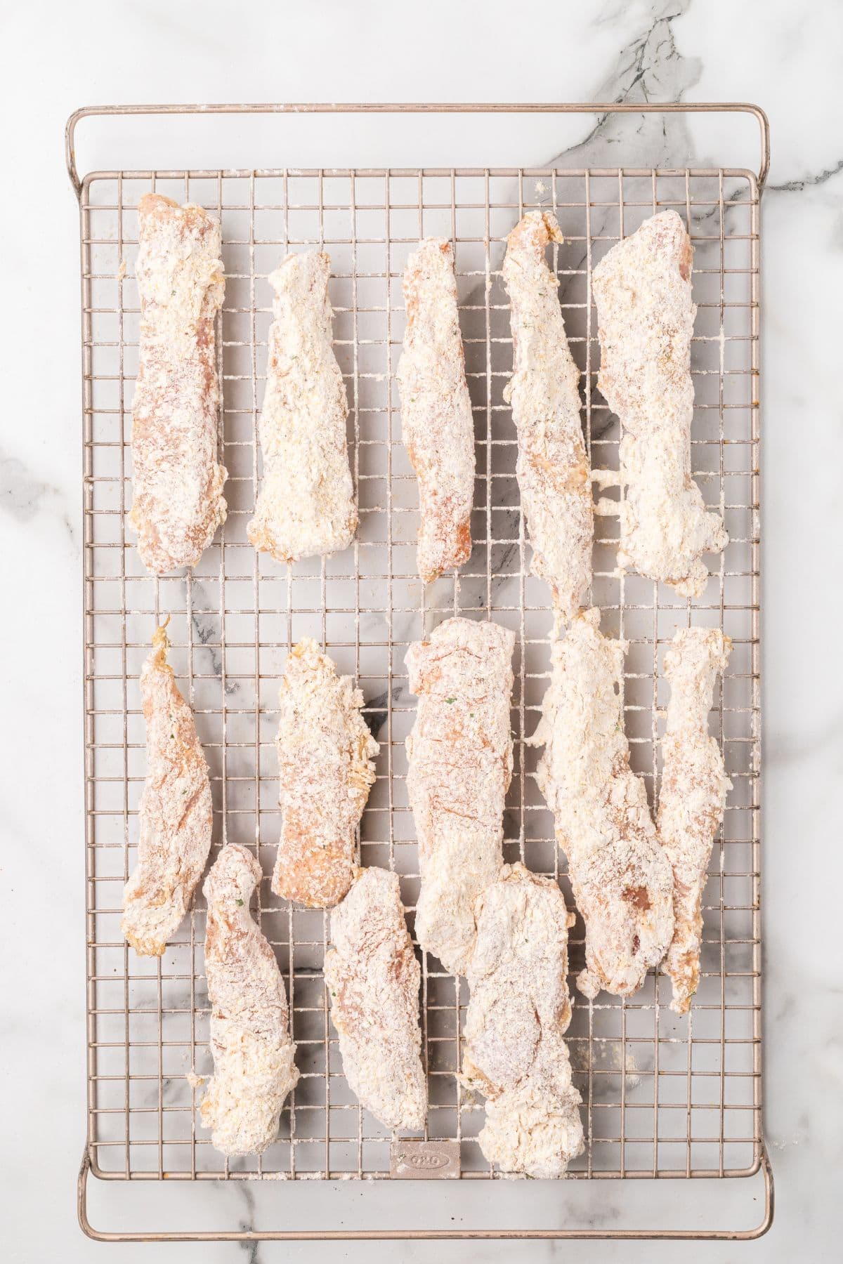 Coated chicken strips resting on a wire rack.