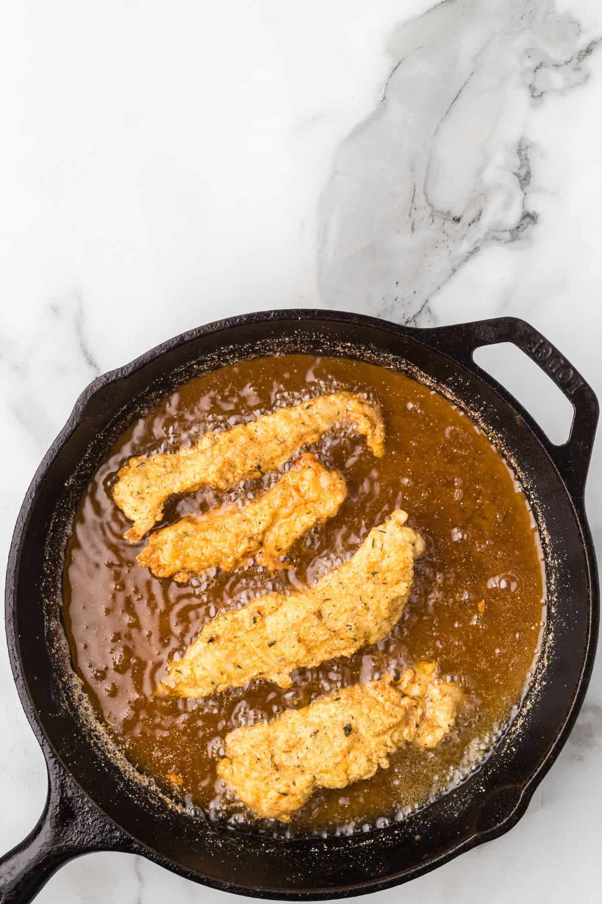 Chicken strips frying in hot oil.
