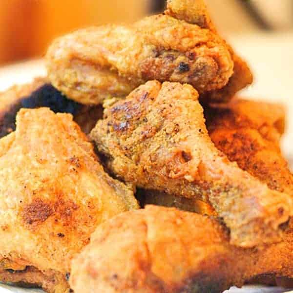 Finished fried chicken piled up on a serving plate.