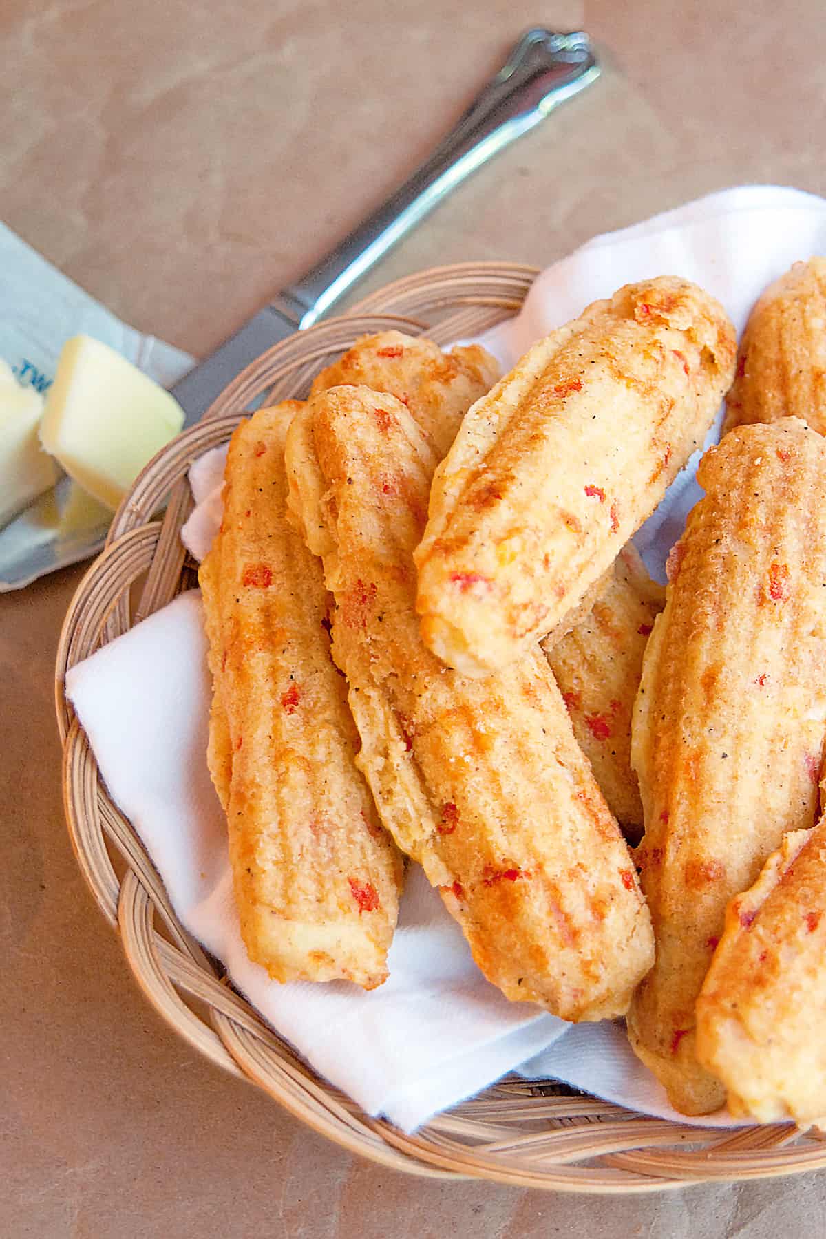 Pimiento Cheese Corn Sticks in a basket with a knife and butter to the side.