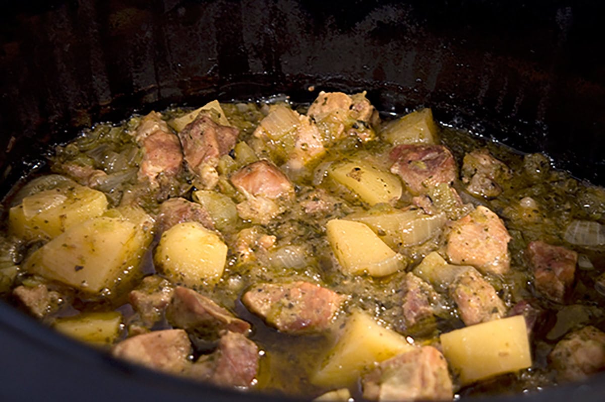 Chunks of meat and potatoes simmer in a flavorful broth inside a slow cooker.