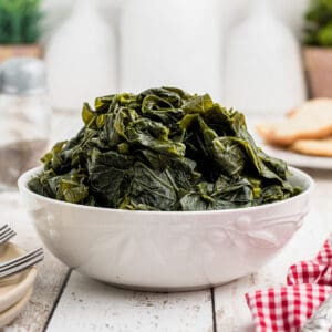 A mound of cooked turnip greens in a white serving bowl.