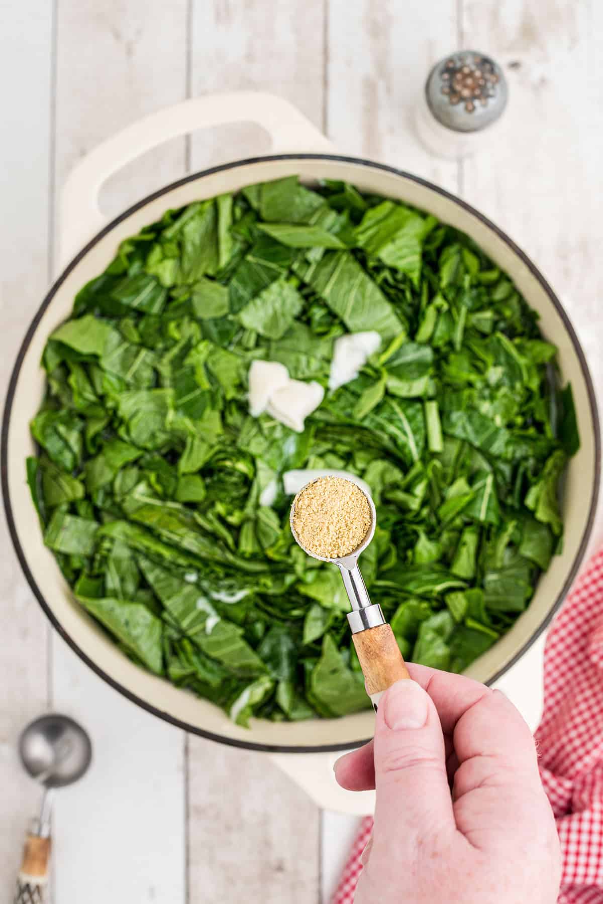 Adding bouillon to a pot of greens.