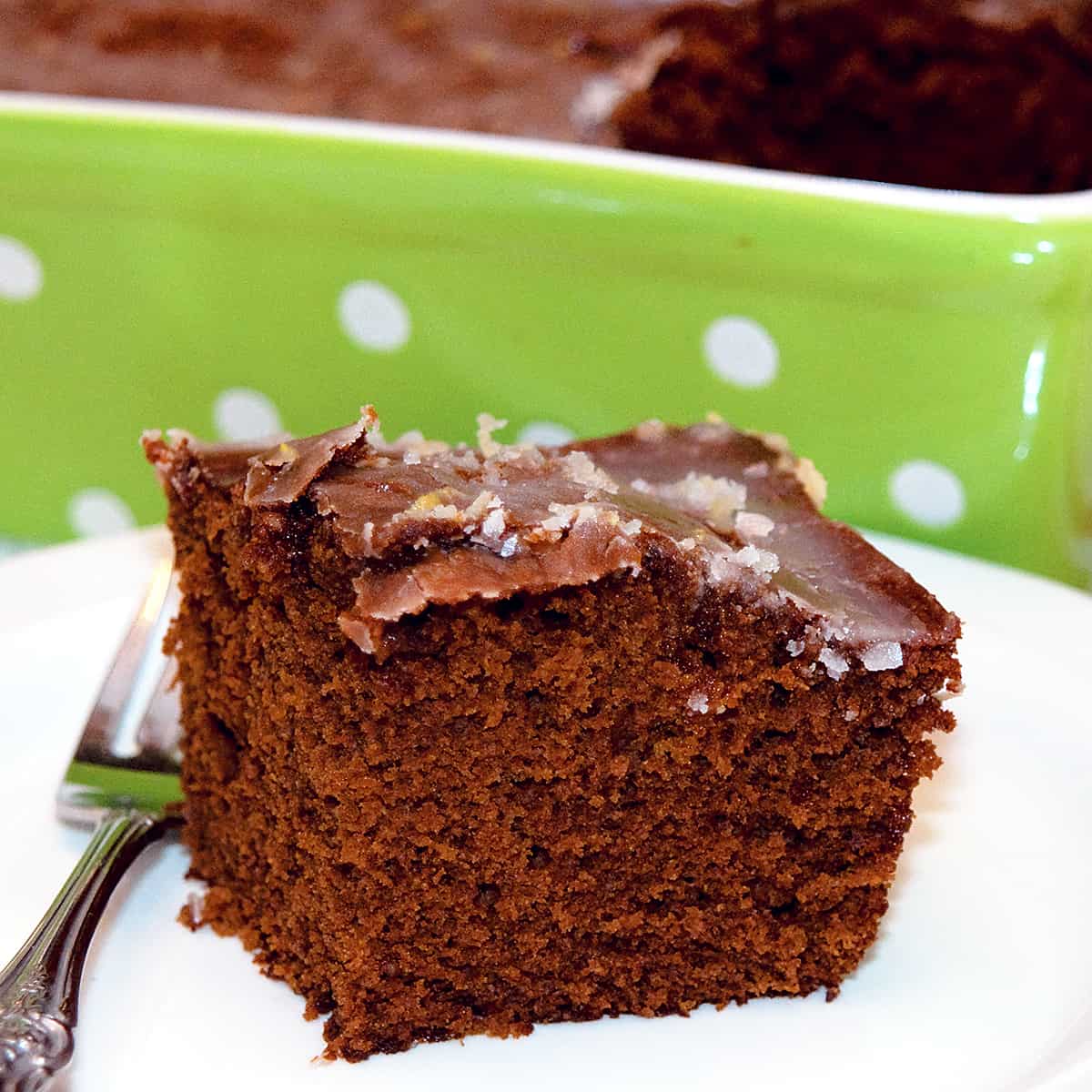 A serving of old fashioned gingerbread with lemon glaze on a serving plate.