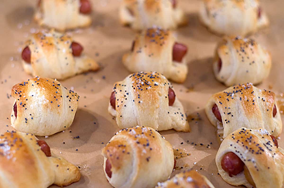 Baked rollups on parchment paper, topped with poppy seeds and baked to a golden brown.