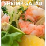 Close-up of shrimp salad with avocado, orange slices, and lettuce, featuring bright citrus flavors.
